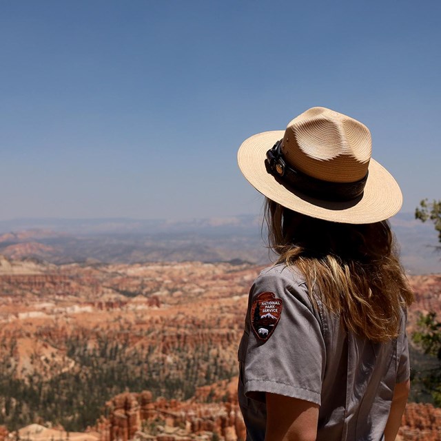 a woman in national park service uniform looks out over bryce canyon