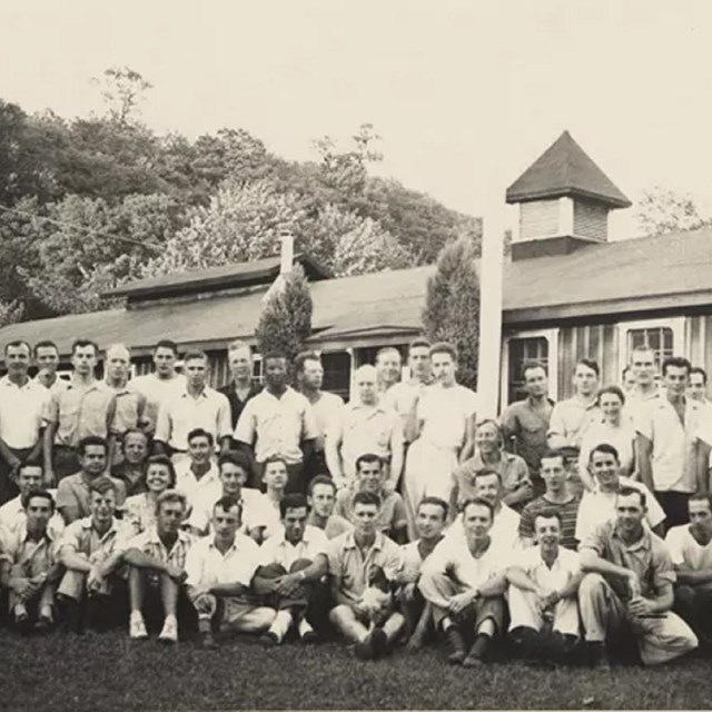 Workers and staff at Camp Patapsco standing in front of a building surrounded by trees