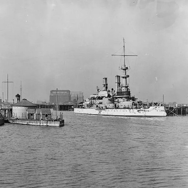 Grey scale image of large naval boats in a harbor
