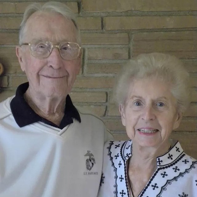 An elderly man and woman hug and smile at the camera