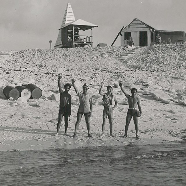 A group of men wave at the ship leaving them behind on Jarvis Island