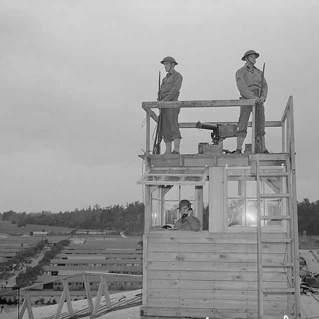 Armed guards on a tower watch over a relocation camp