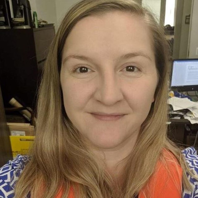 Portrait of Ina looking into the camera in her office. She is wearing a safety vest.