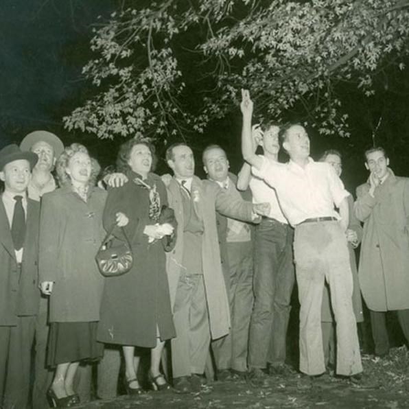 A group of young people stand in a yard under a tree in November 1943.