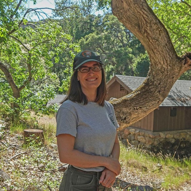 Alicia standing in front of a tree and a building