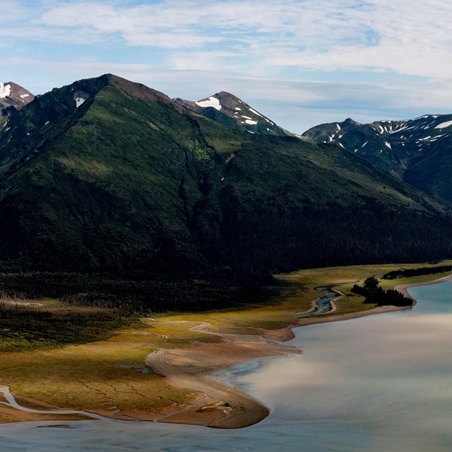 Aerial view of a coastal bay with snow-capped mountains rising from the water's edge.