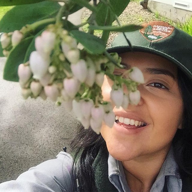 Denise looks up at flowers from a blooming plant