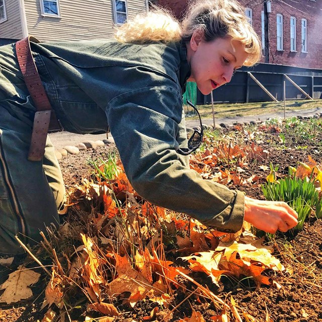 Anna kneeling in a garden, tending plants