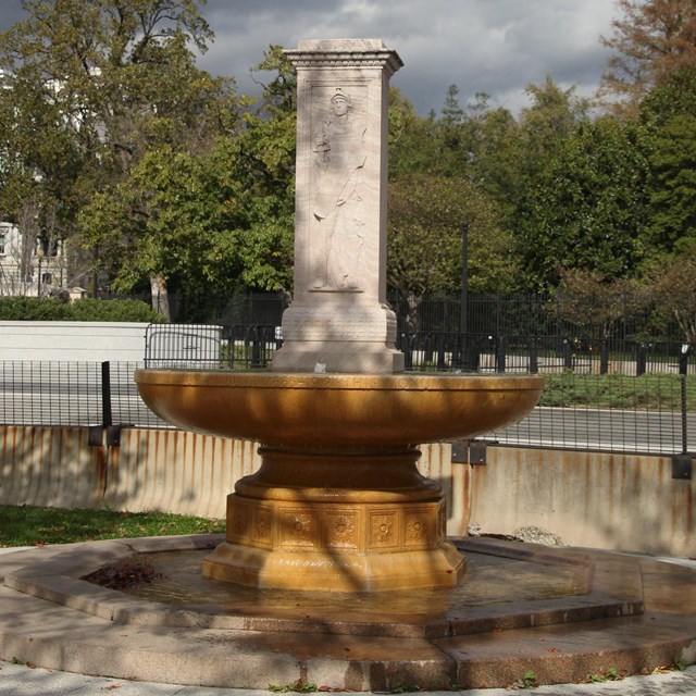 White square column atop a shallow copper basin resting on a pedestal