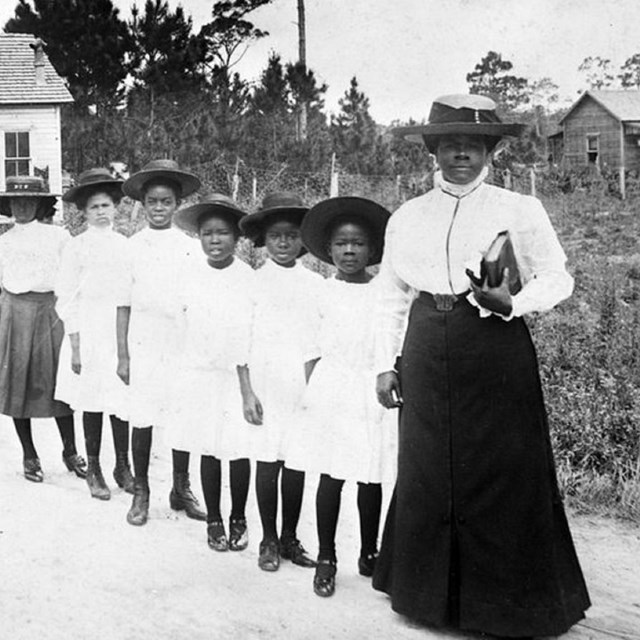 Woman standing with a line of children. 