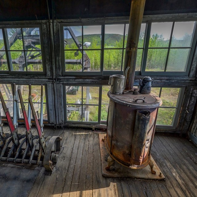 Photograph inside abandoned dredging house of machinery and large windows