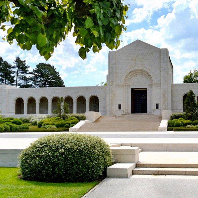 Photograph of white stone chapel with stone terrace and topiary