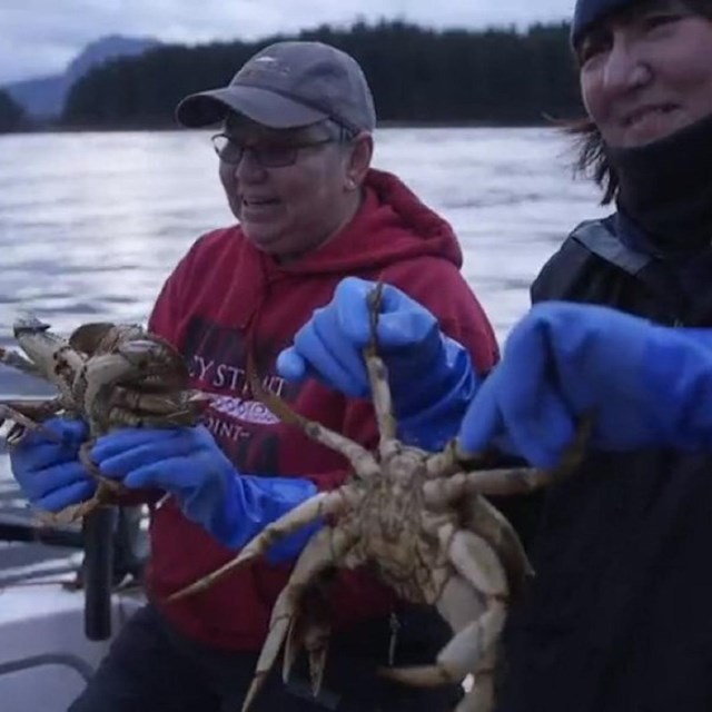 Two women on a boat holding crabs