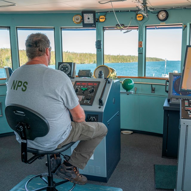 The chief engineer sits in the ship's bridge and steers the ship through Rock Harbor