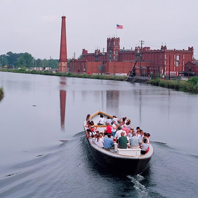 People on boat with brick buildings in background