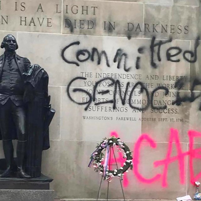 Statue of a solider. Spray painted on the wall next to him is 