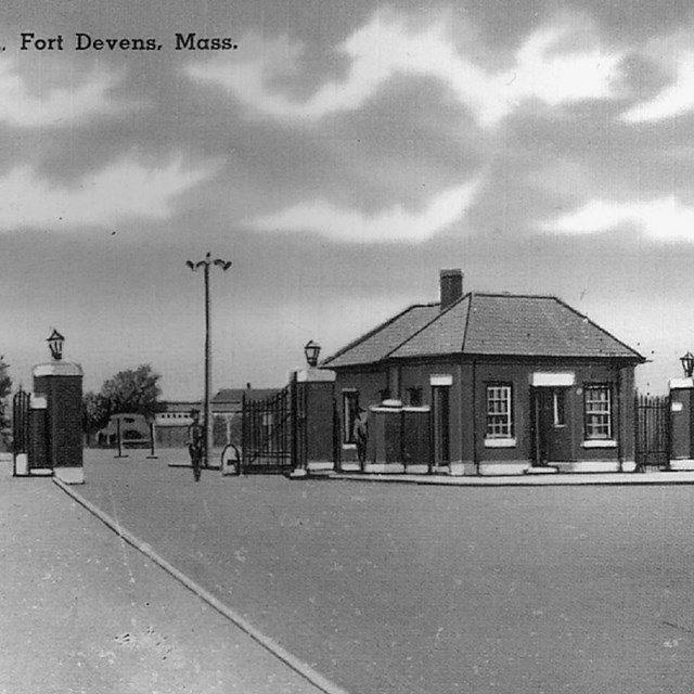 Black and white image of street, fence, and gate house with text 