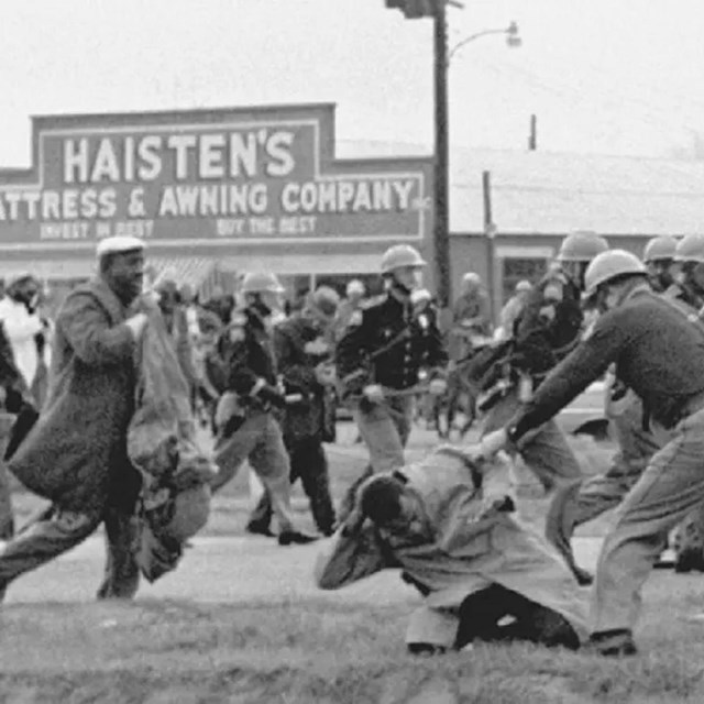 Black man being attacked in the street while people run to intervene 