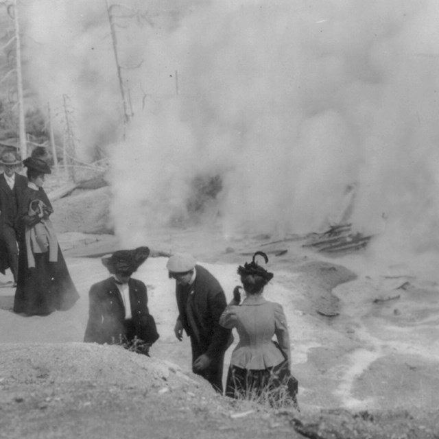 Tourists in Yellowstone Park viewing steaming geysers