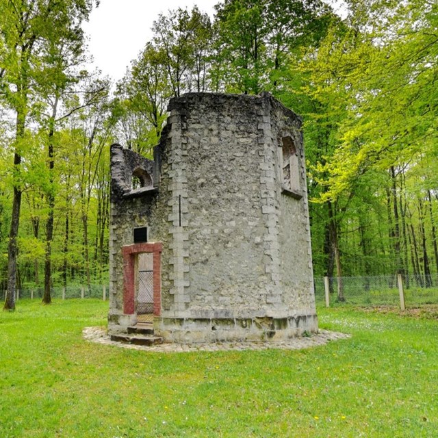 Ruined stone hunting lodge among green trees