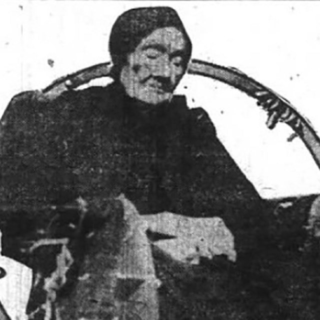 Black and white photo of a seated elderly woman.