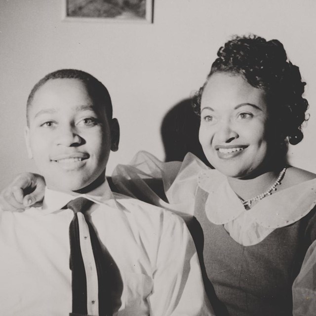 An African American woman and boy sit and smile toward the camera. 