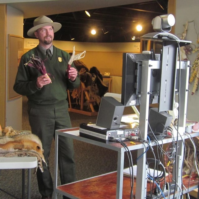 Ranger holding up props to a computer and webcam