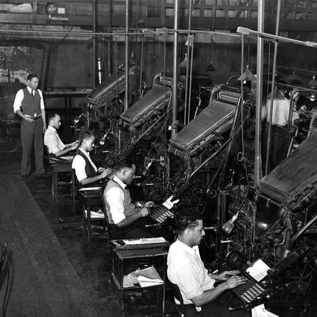 Black men working at large printing machines
