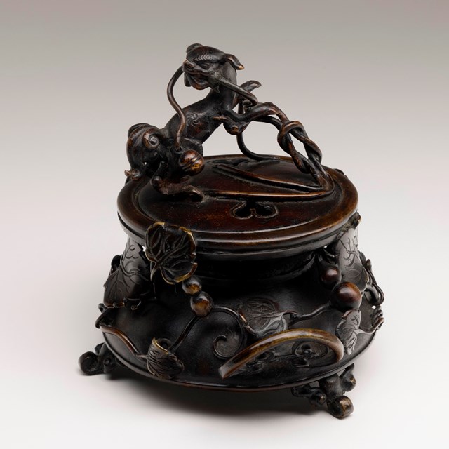 Bronze incense burner with raised vine decoration and sacred dog finial.