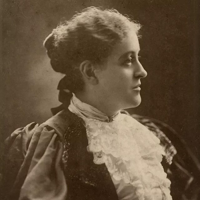 A white woman in profile with pale hair and dressed in Victorian era clothing