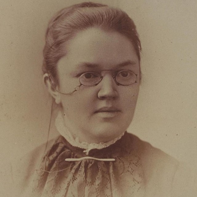 Head and shoulders portrait of woman wearing glasses.