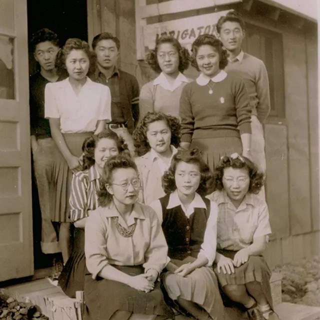 A group of Asian American men and women outside a wooden building