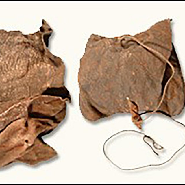 A leather bag holds string, seeds, and other matter