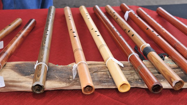 Row of wooden flutes lined up on red tablecloth