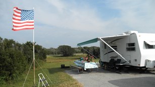 Camping site with RV, picnic table, chairs and American flag