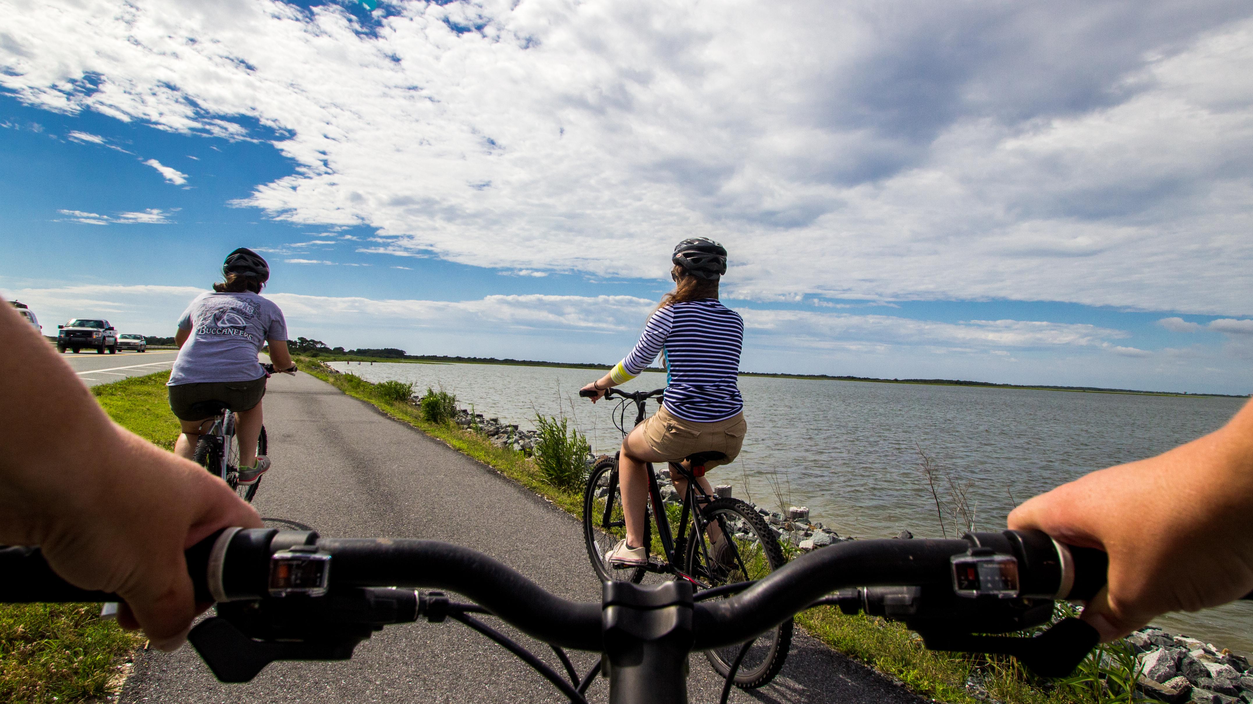 visitors bicycling on a paved path as seen from a bicycler's perspective