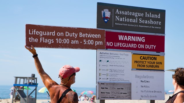 lifeguard updating beach & surf conditions display board at the beach