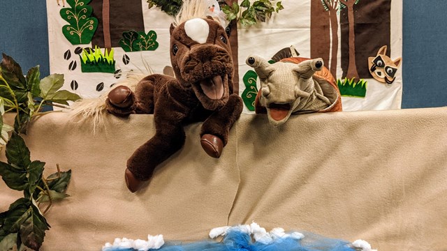 horse and snail puppet in front of ocean and forest puppet theater backdrop