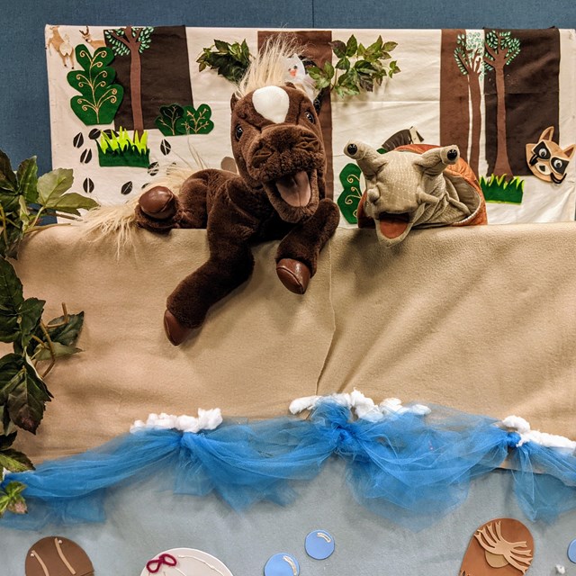 horse and snail puppet in front of ocean and forest puppet theater backdrop