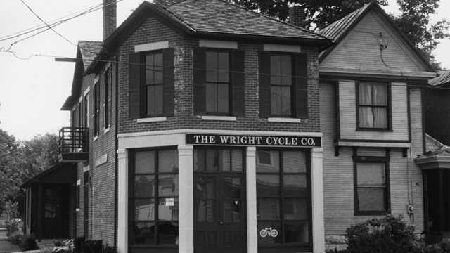 A two-story brick building with many glass windows on the first floor