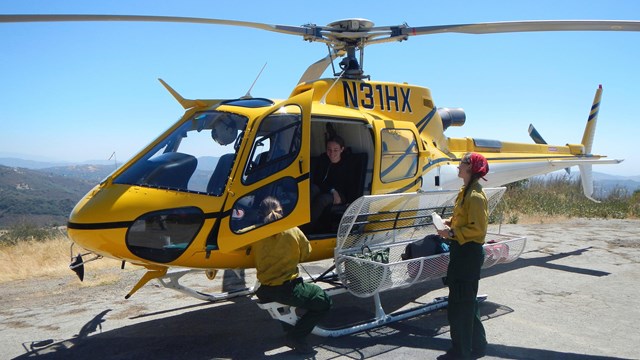 Helitack crewmembers standing next to a helicopter.