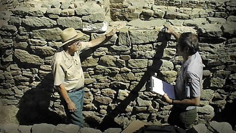A volunteer and ranger discussing a part of the ruin.