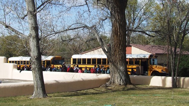School busses and students arrive at Aztec Ruins parking area.