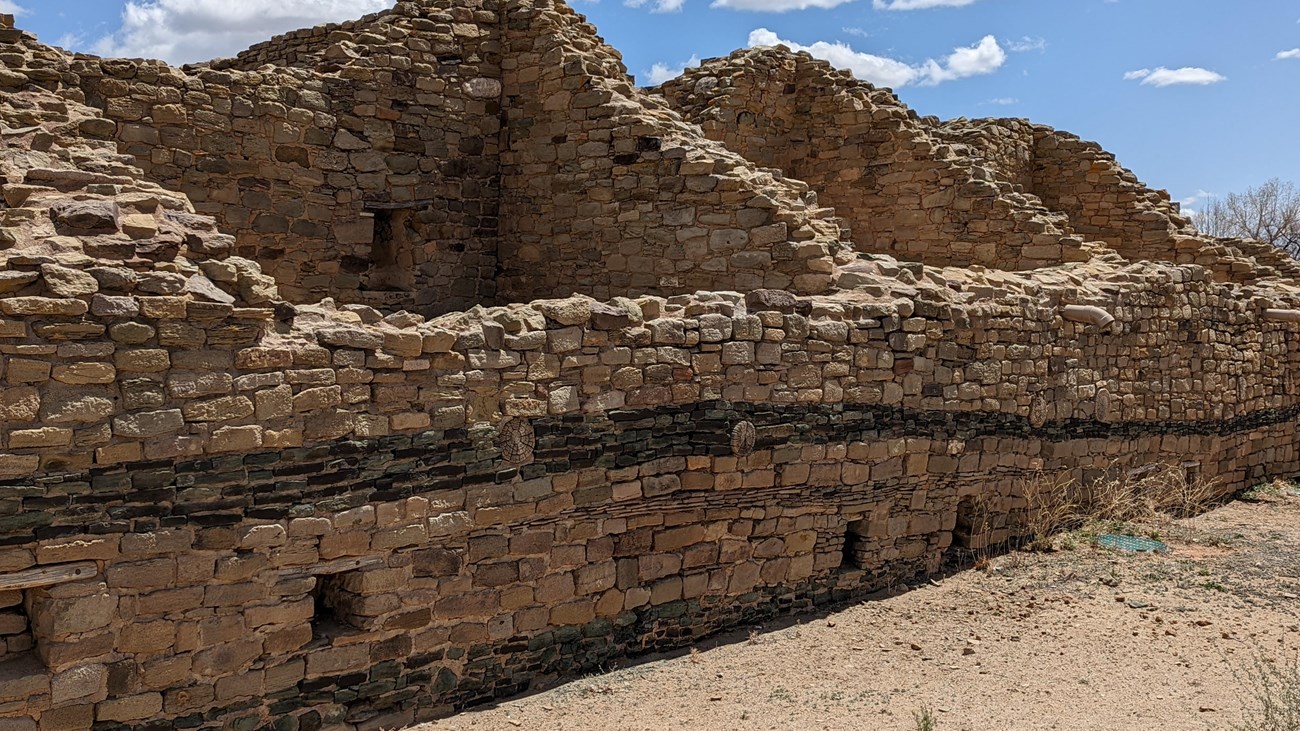 A wall of sandstone blocks with a strip of greywacke in the middle.