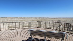 Boardwalk and bench overseeing vast badlands landscape
