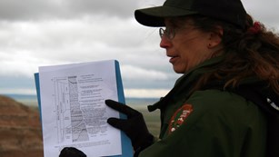 Park ranger displaying a geology guide about rock layers.