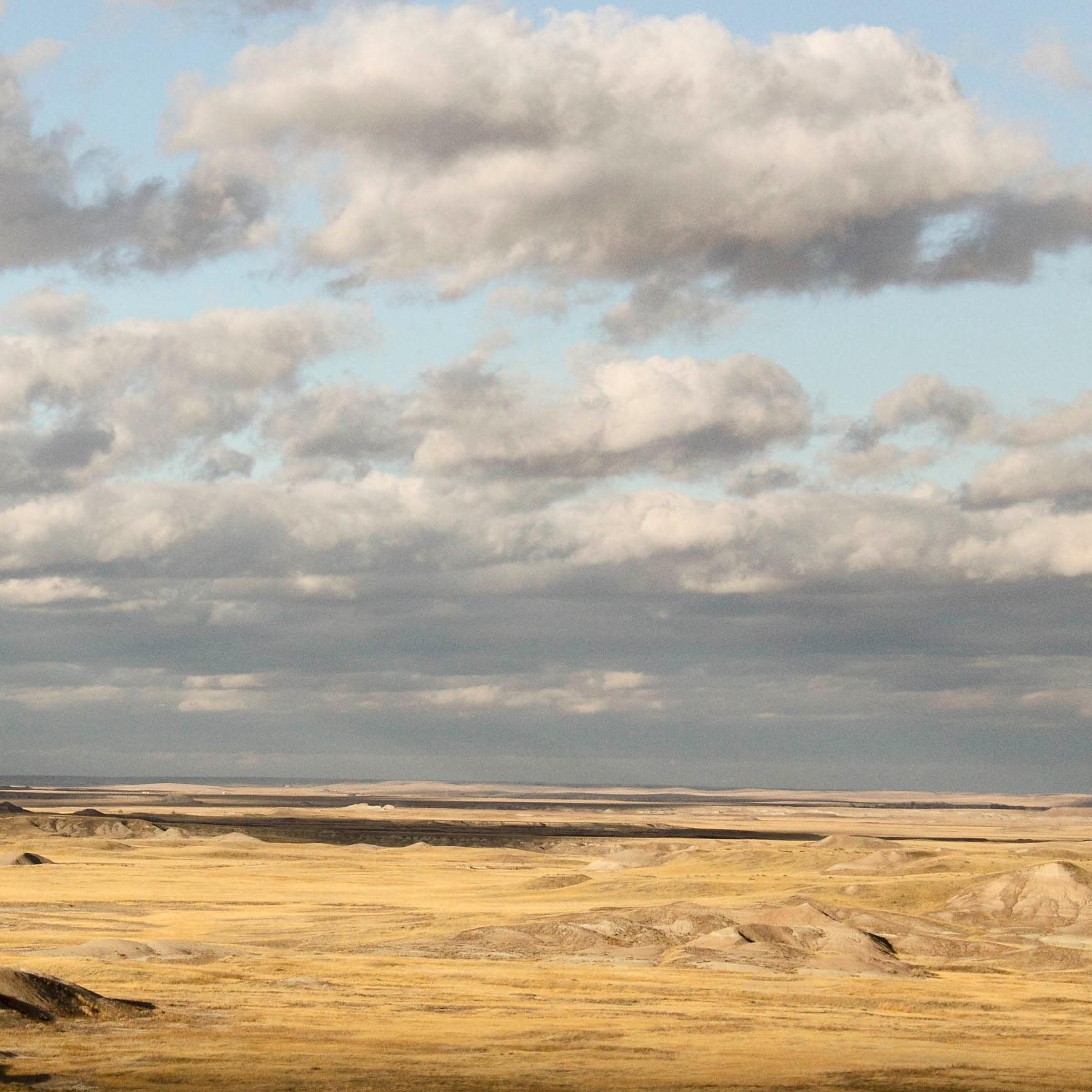 a wide, cloudy sky stretches over rolling plains, drenched in golden sunlight.