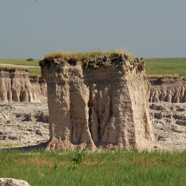 an elevated patch of prairie, roughly cubic, stands above grasses and canyons.