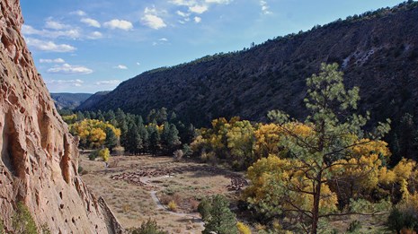 looking down into a canyon with a pueblo and trees with golden leaves