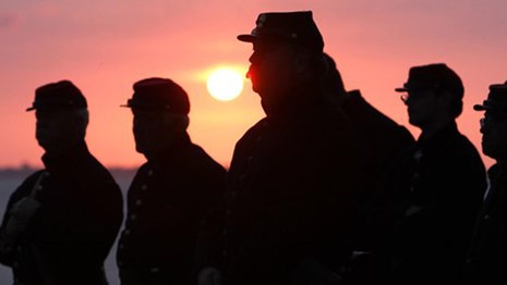 Civil War soldiers silhouetted against pink sunset
